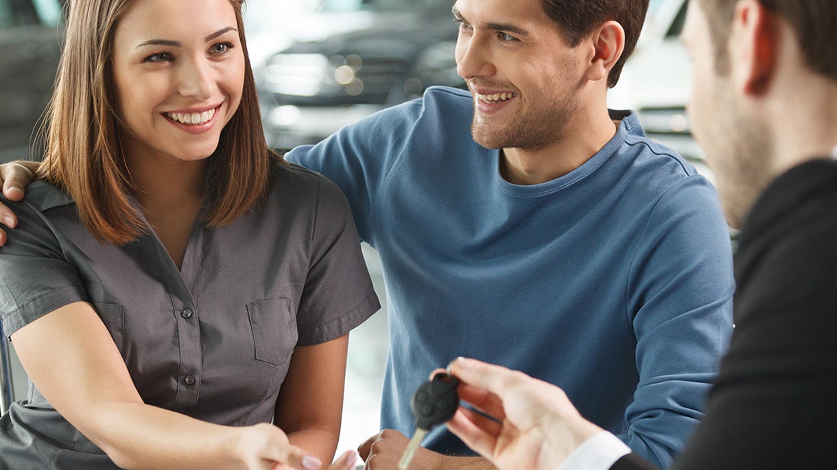 A man and woman being handed car keys