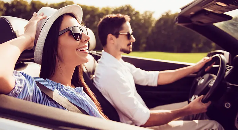 A man and woman driving in a convertable
